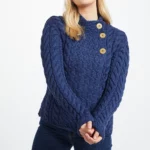 Weibliches Model in asymmetrischer Strickjacke mit Zopfmustern und drei Knöpfen in Persischblau