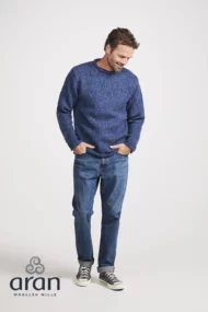 Männliches Modell mit Donegal Tweed Rundhalspullover mit gerolltem Kragen in Denimblau, von Weitem