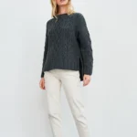 Aran-Pullover in Grau in Kastenform mit Seitenschlitzen. Weibliches Modell mit weissen Hosen trägt Aran Kastenpullover