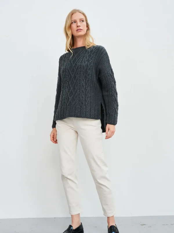 Aran-Pullover in Grau in Kastenform mit Seitenschlitzen. Weibliches Modell mit weissen Hosen trägt Aran Kastenpullover