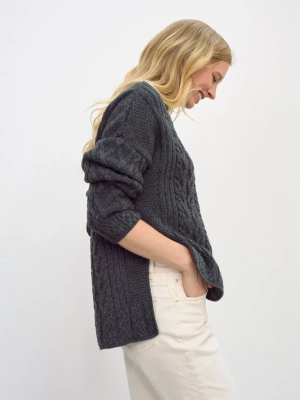 Aran-Pullover in Grau in Kastenform mit Seitenschlitzen. Weibliches Modell mit weissen Hosen trägt Aran Kastenpullover, Seitenansicht